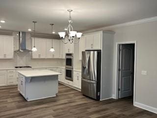 kitchen with a center island, wall chimney exhaust hood, pendant lighting, and appliances with stainless steel finishes