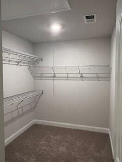 walk in closet featuring dark carpet