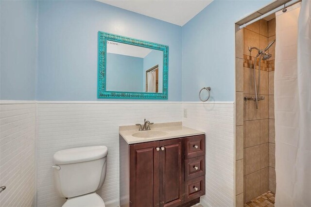 bathroom with a shower with shower curtain, vanity, toilet, and tile walls