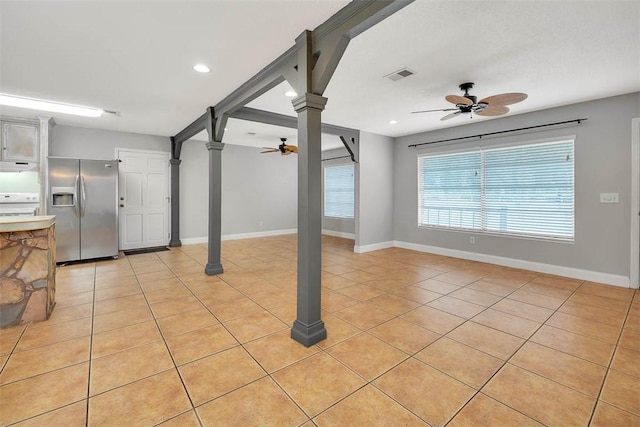 basement featuring stainless steel fridge with ice dispenser, light tile patterned floors, and ceiling fan