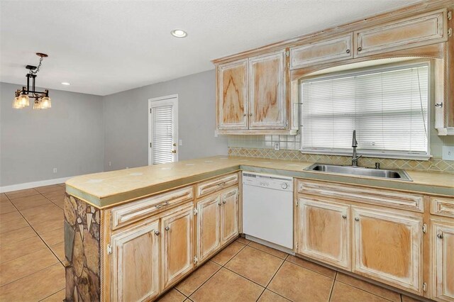 kitchen featuring kitchen peninsula, white dishwasher, hanging light fixtures, and sink