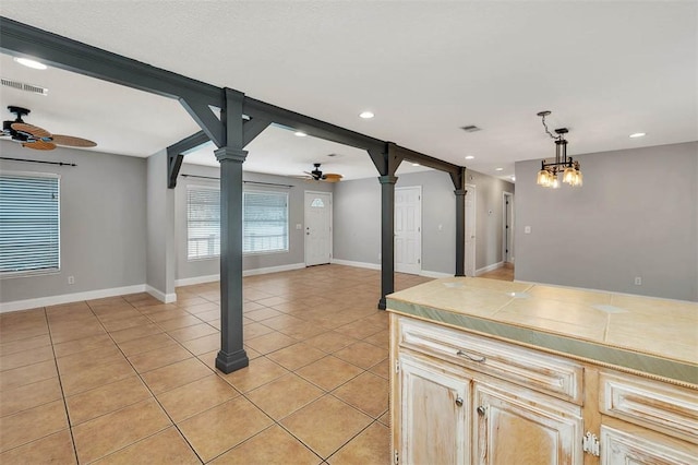kitchen with ceiling fan, light tile patterned floors, hanging light fixtures, and decorative columns