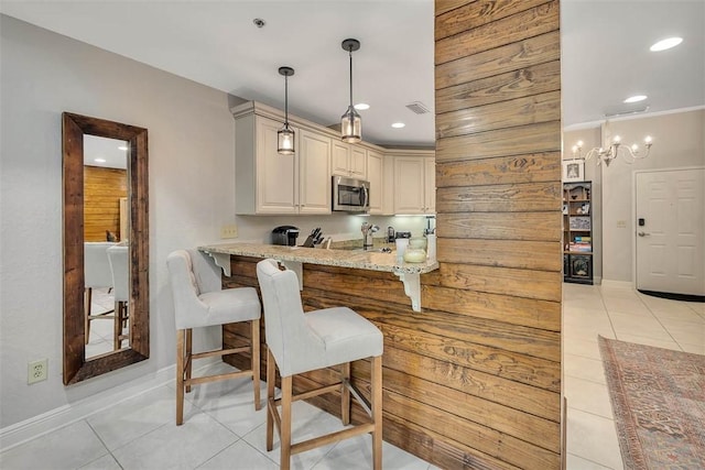 150 Salt Air Dr Unit 202, Saint Simons Island, GA 31522 - kitchen with stainless steel microwave, light tile patterned floors, a breakfast bar, light stone countertops, and recessed lighting