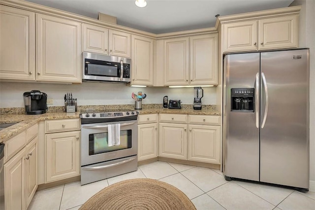 150 Salt Air Dr Unit 202, Saint Simons Island, GA 31522 - kitchen featuring appliances with stainless steel finishes, cream cabinets, light tile patterned floors, and light stone counters