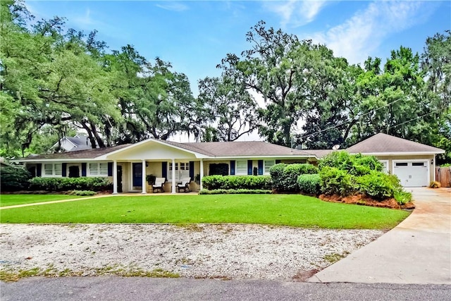 ranch-style home featuring a garage, covered porch, and a front yard