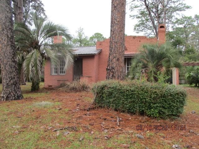 view of front of house with a chimney and metal roof