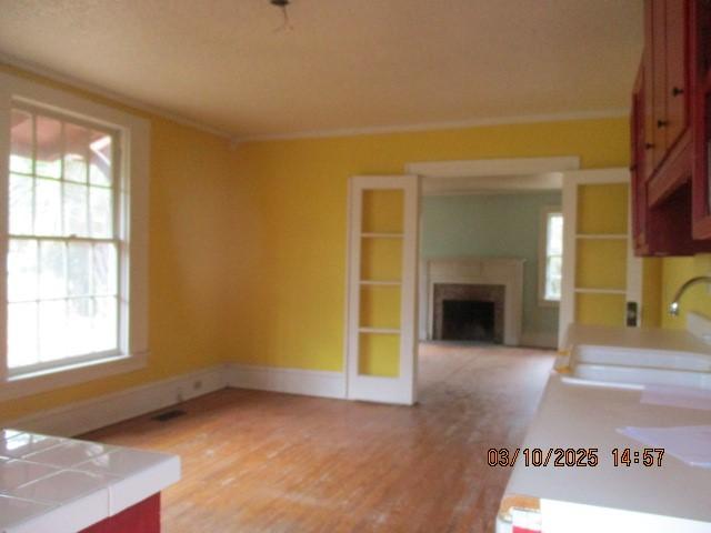 unfurnished living room with a fireplace, a sink, light wood-style flooring, and a healthy amount of sunlight