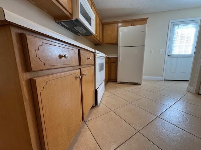 kitchen featuring light tile patterned flooring and white appliances