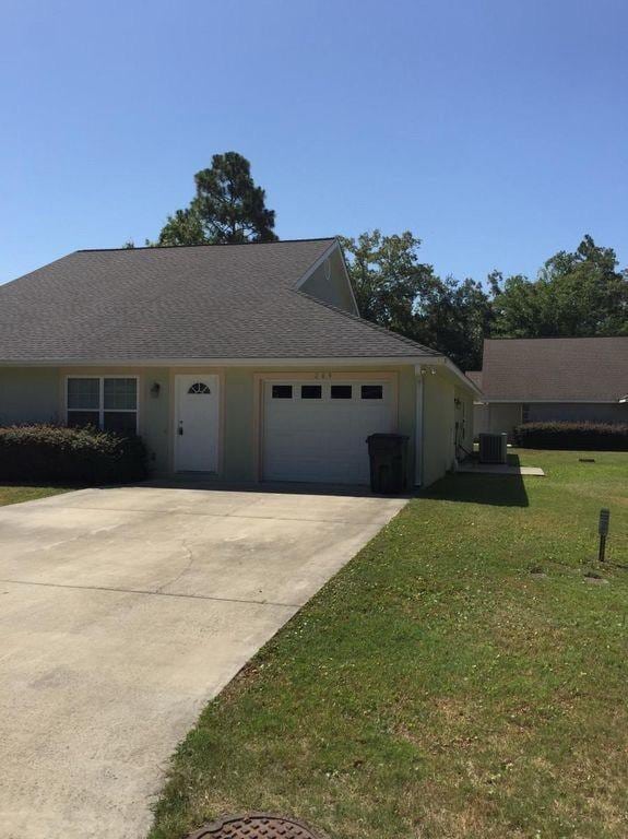 view of front facade featuring a front yard, a garage, and central air condition unit