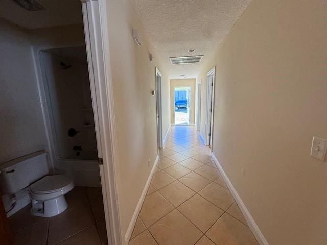 hall with light tile patterned floors and a textured ceiling