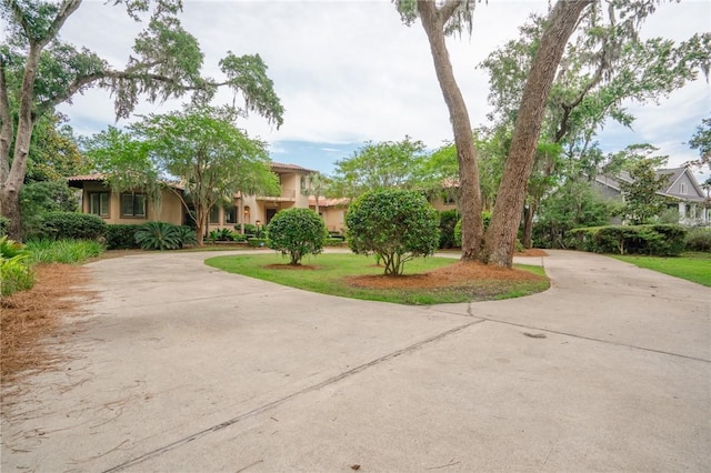 178 Hampton Point Dr, Saint Simons Island, GA 31522 - obstructed view of property with curved driveway, stucco siding, and a tiled roof