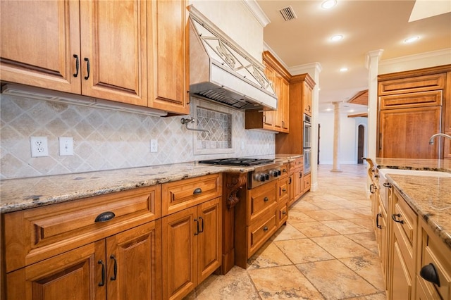 178 Hampton Point Dr, Saint Simons Island, GA 31522 - kitchen with crown molding, stainless steel gas cooktop, ornate columns, custom exhaust hood, and decorative backsplash