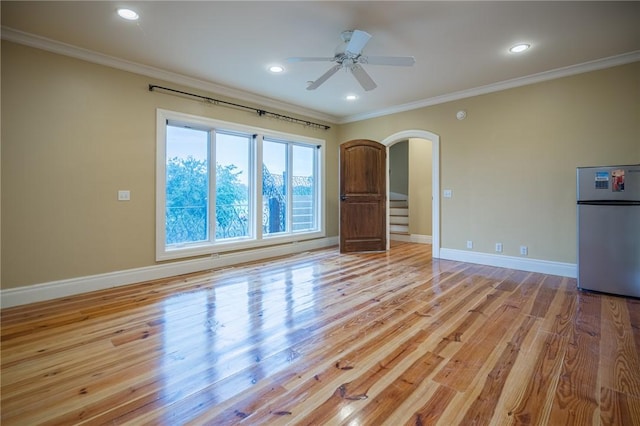 178 Hampton Point Dr, Saint Simons Island, GA 31522 - empty room with arched walkways, crown molding, light wood-style flooring, ceiling fan, and stairway