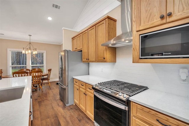 kitchen with appliances with stainless steel finishes, backsplash, dark hardwood / wood-style flooring, ornamental molding, and wall chimney range hood