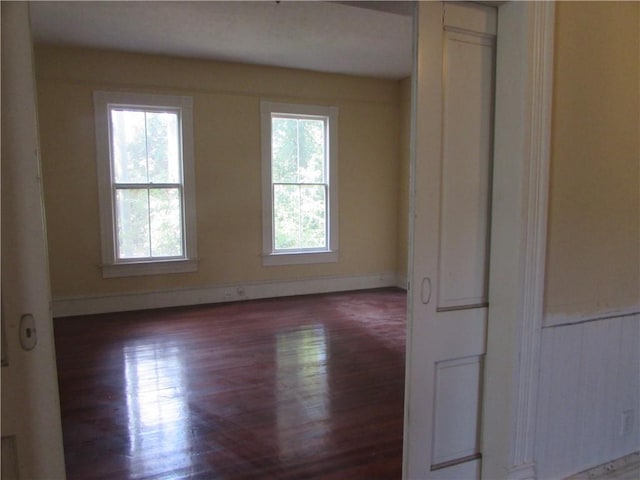 unfurnished room featuring dark wood-type flooring and a healthy amount of sunlight