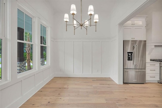 128 W Point Pkwy, Saint Simons Island, GA 31522 - unfurnished dining area featuring a decorative wall, light wood-style flooring, a chandelier, and wainscoting