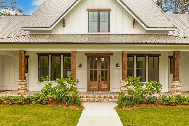 128 W Point Pkwy, Saint Simons Island, GA 31522 - property entrance with covered porch, board and batten siding, and a yard