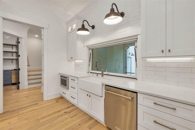 128 W Point Pkwy, Saint Simons Island, GA 31522 - kitchen with stainless steel dishwasher, a sink, light countertops, tasteful backsplash, and white cabinetry