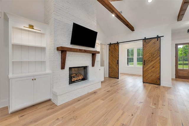 128 W Point Pkwy, Saint Simons Island, GA 31522 - unfurnished living room featuring a barn door, light wood-style floors, beam ceiling, a fireplace, and baseboards
