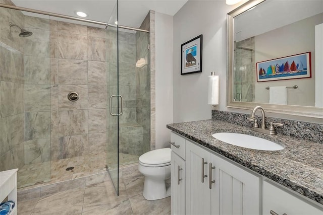 bathroom featuring a shower with door, vanity, and toilet