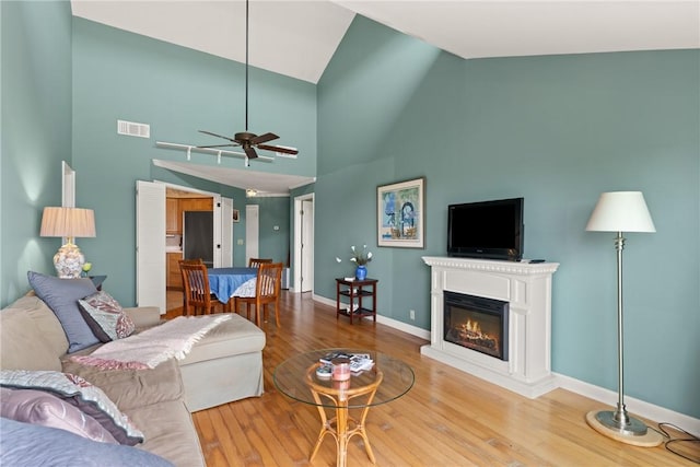 345 Moss Oak Cir, Saint Simons Island, GA 31522 - living room featuring a glass covered fireplace, wood finished floors, a ceiling fan, and high vaulted ceiling