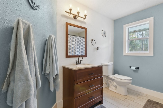 bathroom with toilet, baseboards, wood finished floors, and vanity