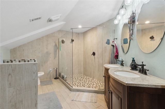 bathroom with toilet, a sink, visible vents, vaulted ceiling, and a shower stall