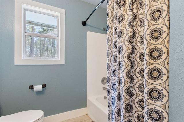 full bathroom with toilet, baseboards, and shower / bath combo with shower curtain