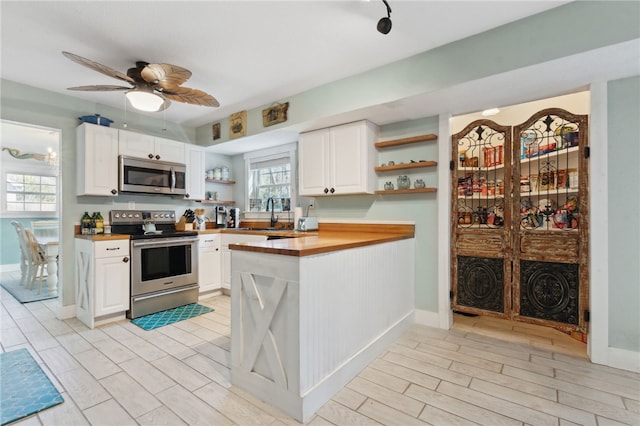 kitchen with stainless steel appliances, wood finish floors, white cabinets, and open shelves