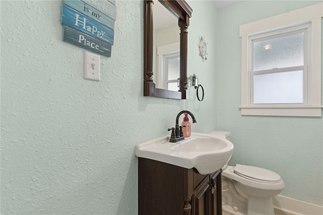 half bathroom featuring baseboards, vanity, and toilet