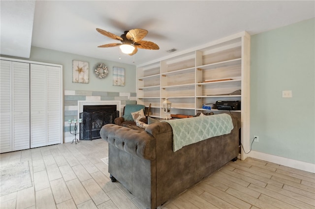 living room featuring a fireplace, visible vents, baseboards, a ceiling fan, and light wood-type flooring