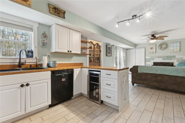 kitchen with wine cooler, black dishwasher, a fireplace, a sink, and a peninsula