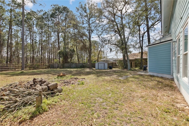 view of yard with an outdoor fire pit, a fenced backyard, an outbuilding, and a shed