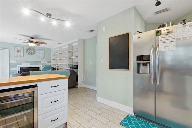 kitchen with wine cooler, visible vents, white cabinets, wood tiled floor, and stainless steel fridge