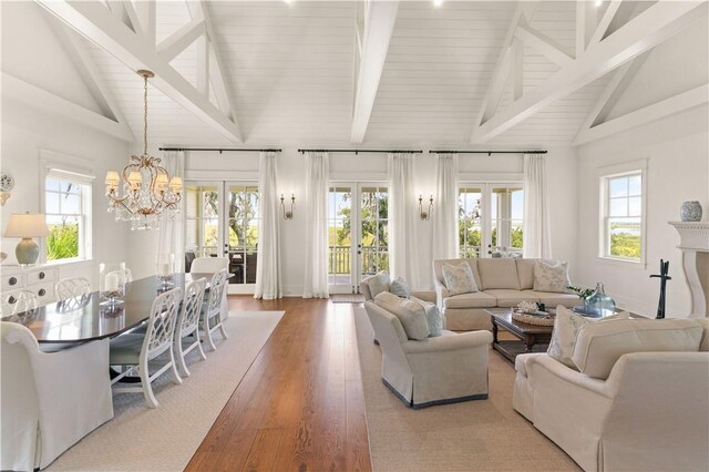 living room with hardwood / wood-style floors, a notable chandelier, high vaulted ceiling, and french doors