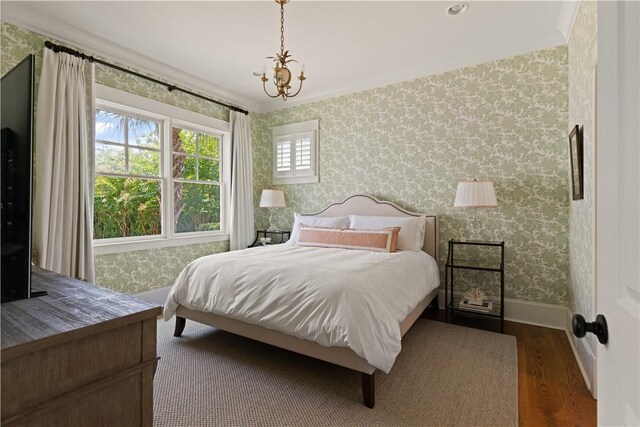 bedroom featuring dark hardwood / wood-style floors, an inviting chandelier, and ornamental molding