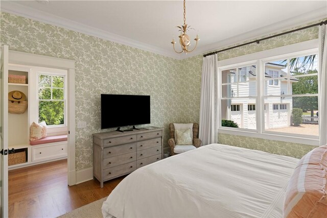 bedroom featuring ornamental molding, a notable chandelier, and hardwood / wood-style flooring