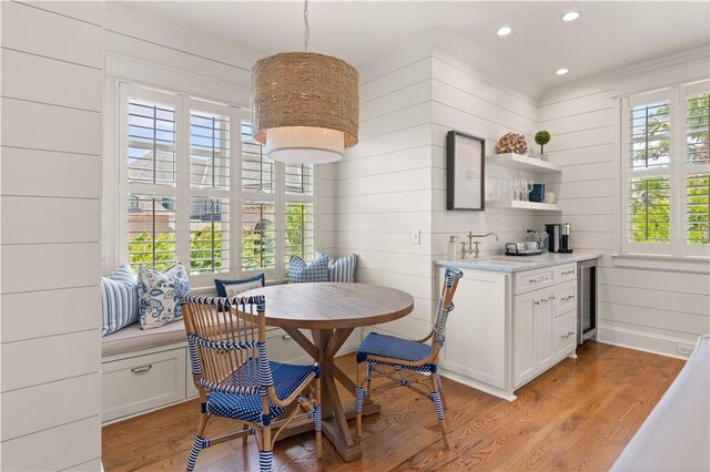 dining area with wood walls, plenty of natural light, and light hardwood / wood-style floors