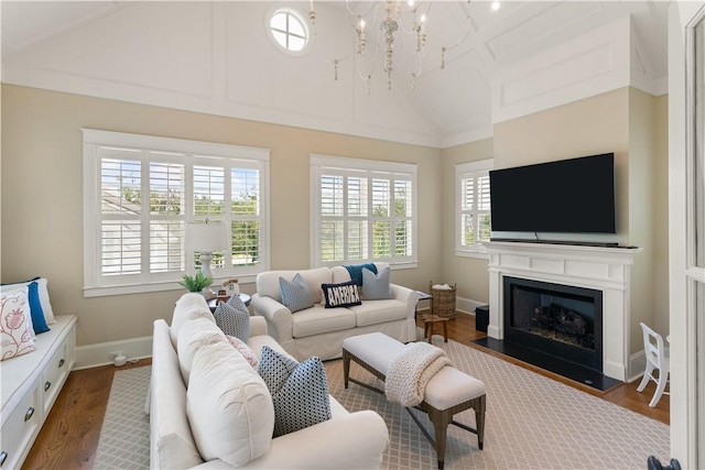 living room with plenty of natural light, an inviting chandelier, wood-type flooring, and lofted ceiling