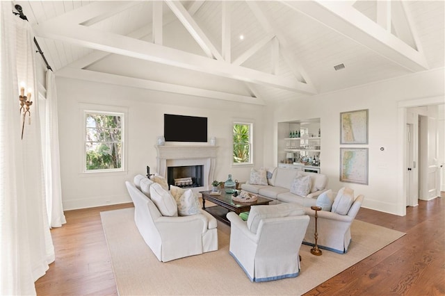 living room featuring beamed ceiling, hardwood / wood-style floors, and bar