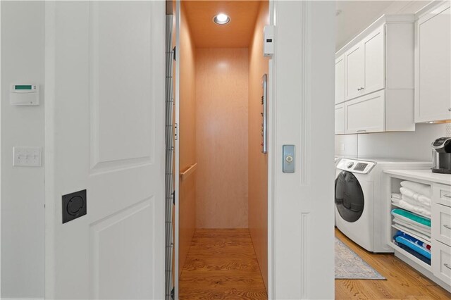 clothes washing area featuring light hardwood / wood-style floors, cabinets, and washer / clothes dryer