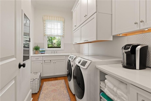 laundry room featuring washer and dryer, cabinets, sink, and light hardwood / wood-style flooring