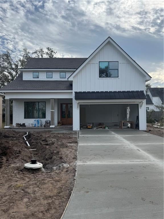 modern inspired farmhouse featuring driveway, french doors, board and batten siding, and an attached garage