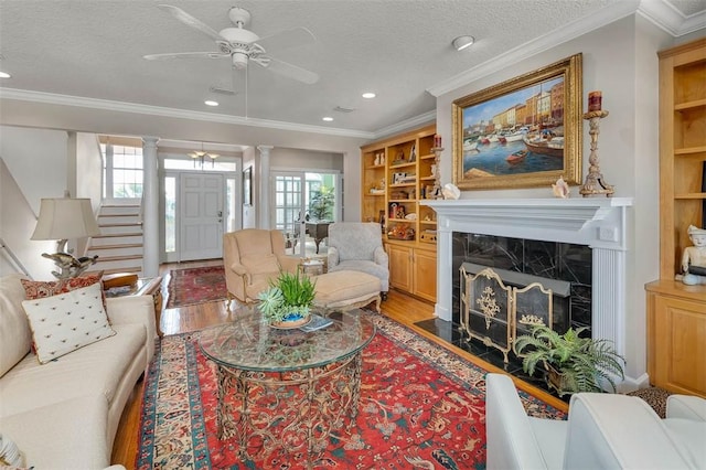 living room with built in shelves, a premium fireplace, a healthy amount of sunlight, and a textured ceiling