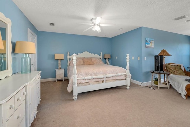 bedroom featuring ceiling fan, light colored carpet, and a textured ceiling