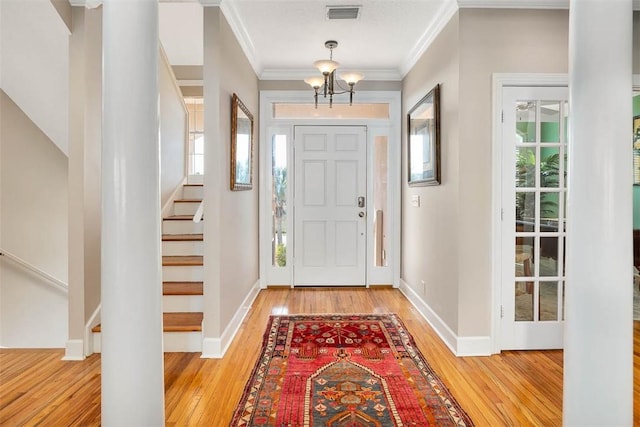 foyer entrance with an inviting chandelier, ornamental molding, and light hardwood / wood-style flooring