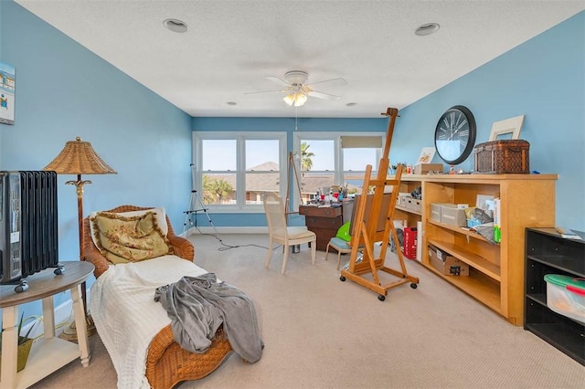 living area with ceiling fan, carpet floors, a textured ceiling, and radiator