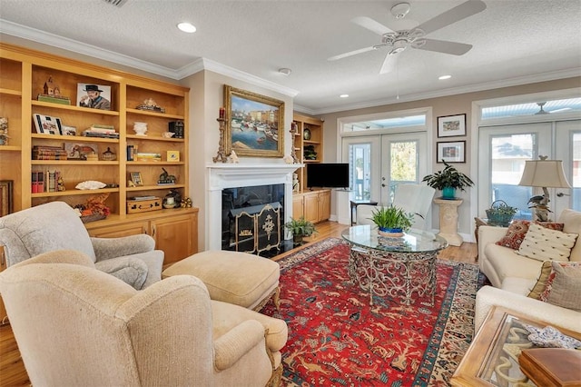 living room with french doors, light wood-type flooring, a textured ceiling, ceiling fan, and a premium fireplace