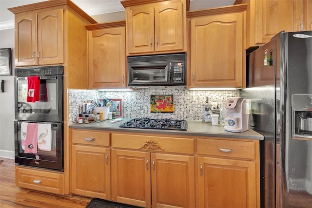 kitchen with backsplash, crown molding, black appliances, and light hardwood / wood-style floors