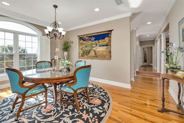 dining room featuring a notable chandelier, light hardwood / wood-style floors, ornamental molding, and decorative columns